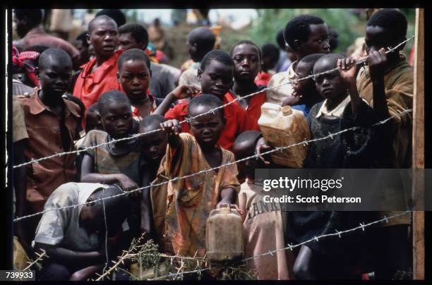 Youths gather behind the fence of a refugee camp May 3, 1994 at the border of Rwanda and Tanzania. Hutu refugees have fled to Tanzania across the...