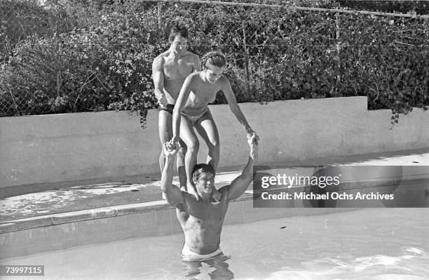 Actor and body builder Arnold Schwarzenegger plays with a topless Nastassja Kinski on his shoulders in a pool in 1976 in Los Angeles, California.