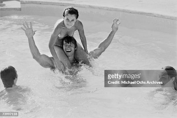 Actor and bodybuilder, Arnold Schwarzenegger , with a topless Nastassja Kinski on his shoulders in a swimming pool in Los Angeles, California, 1976....