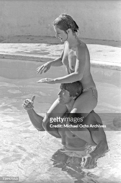 Actor and body builder Arnold Schwarzenegger plays with a topless Nastassja Kinski on his shoulders in a pool in 1976 in Los Angeles, California.