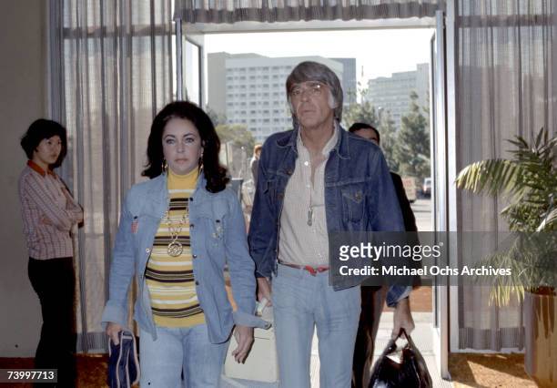 Actress Elizabeth Taylor enters a building with actor Peter Lawford circa 1975.