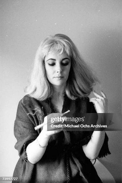 Actress Elizabeth Taylor poses for a portrait session wearing a blonde wig while fixing her make up and hair in 1963.