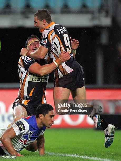 Robbie Farah congratulates teammate Chris Heighington of the West Tigers after he scored in try by sliding in front of Willie Tonga of the Bulldogs...