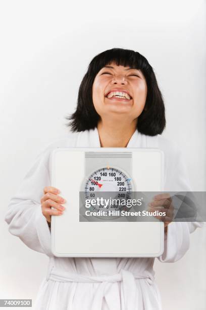 portrait of asian woman holding bathroom scale - hill street studios bildbanksfoton och bilder