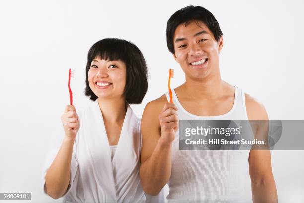 portrait of asian couple holding toothbrushes - toothbrush ストックフォトと画像