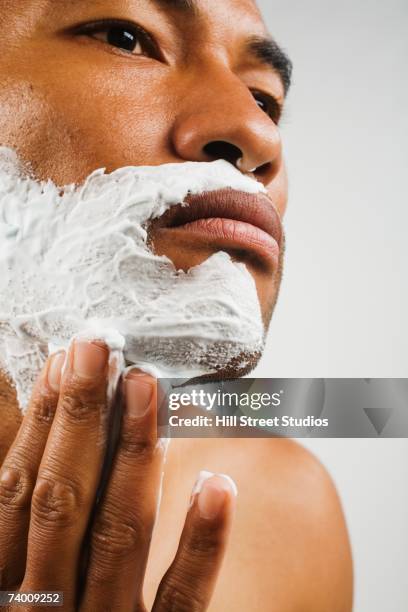 asian man applying shaving cream - man shaving face stock-fotos und bilder