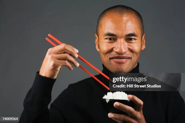 asian man eating rice with chopsticks - palillos chinos fotografías e imágenes de stock