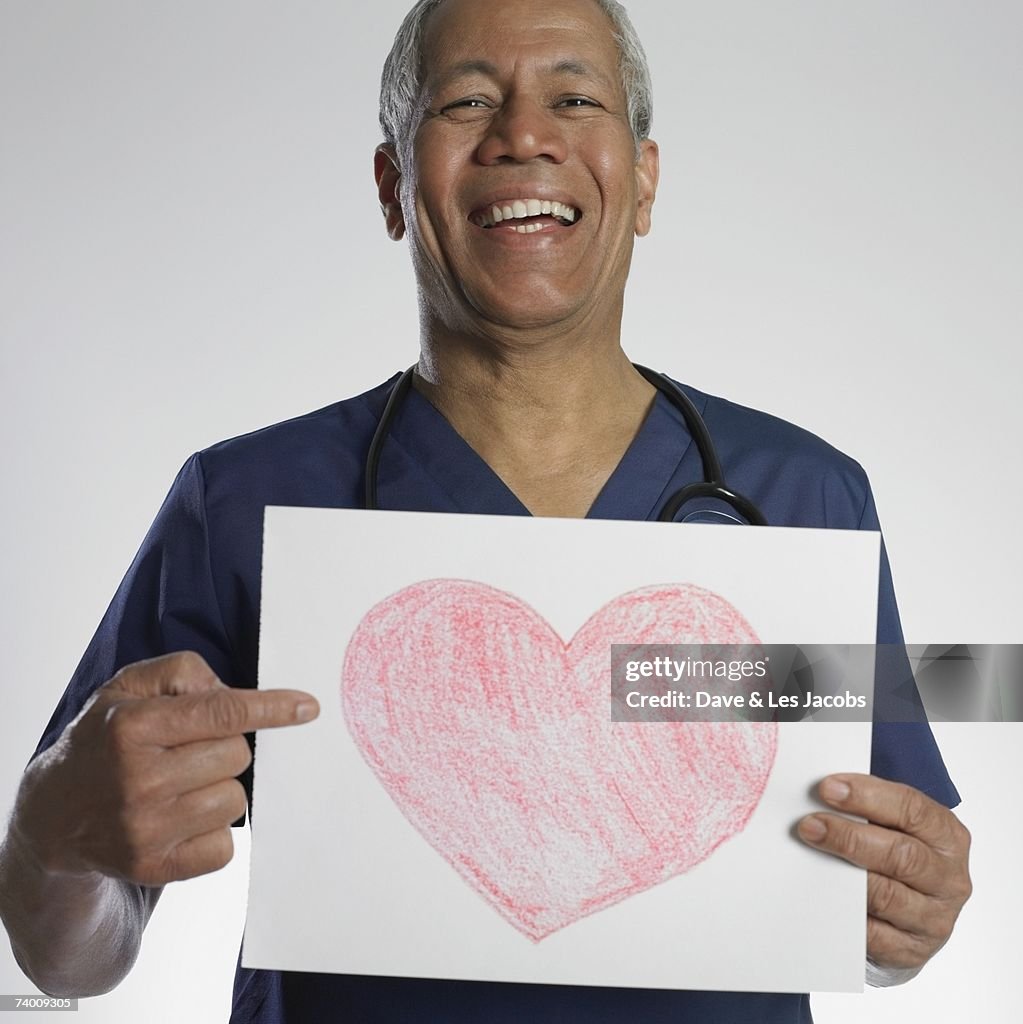 Indian male doctor holding heart drawing
