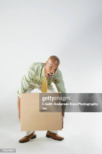 african businessman lifting box - box lifting technique stock-fotos und bilder