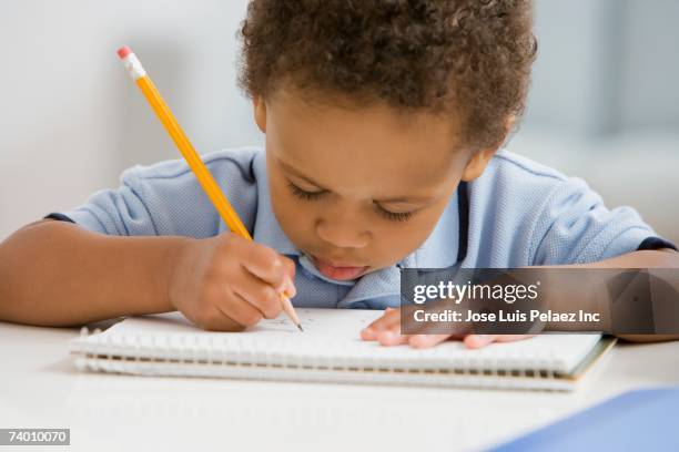 african boy drawing on notebook - ortografia fotografías e imágenes de stock