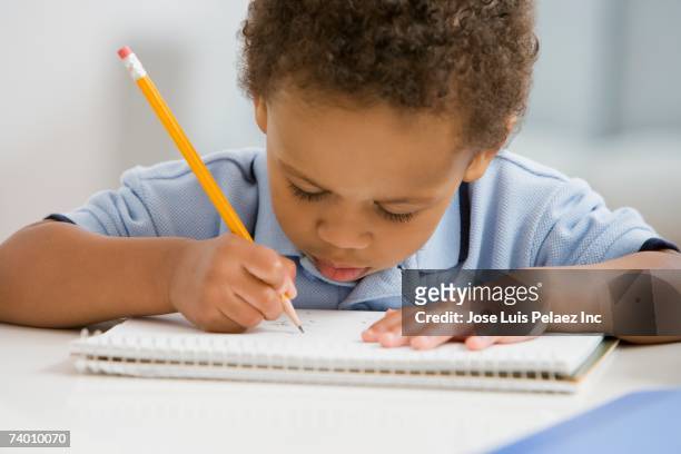 african boy drawing on notebook - spelling stock photos et images de collection