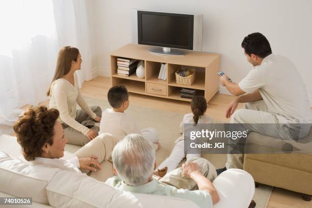 multi-generational hispanic family watching television - family watching tv from behind stockfoto's en -beelden