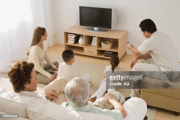multi-generational hispanic family watching television - family watching tv from behind stock pictures, royalty-free photos & images