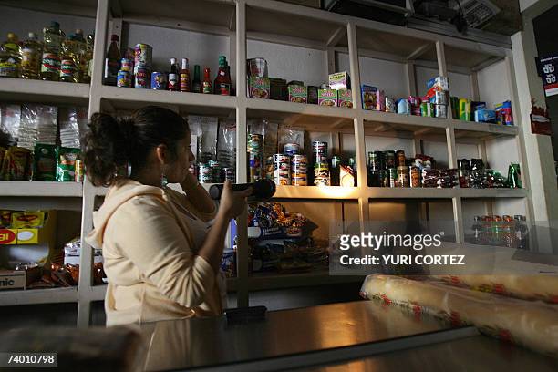 Una dependiente de tienda se auxilia de una linterna para buscar productos en la estanteria el 27 de abril de 2007 durante un corte de energia...
