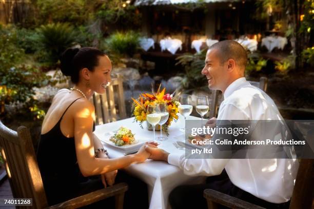 couple holding hands at restaurant table - couple fine dining stock pictures, royalty-free photos & images