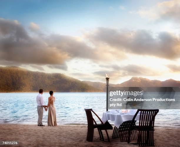 couple next to table set for two at beach - picknick edel stock-fotos und bilder