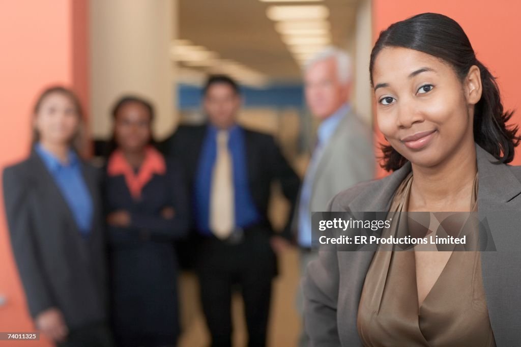 African businesswoman with co-workers in background