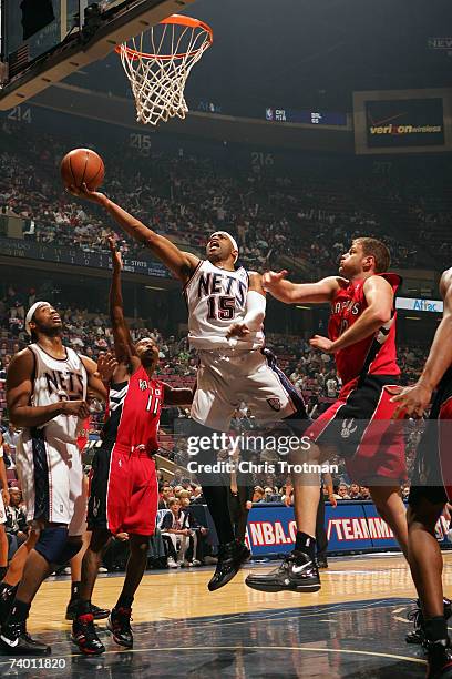 Vince Carter of the New Jersey Nets goes to the hoop inbetween of the New Jersey Nets Rasho Nesterovic and T.J. Ford of the Toronto Raptors in Game...