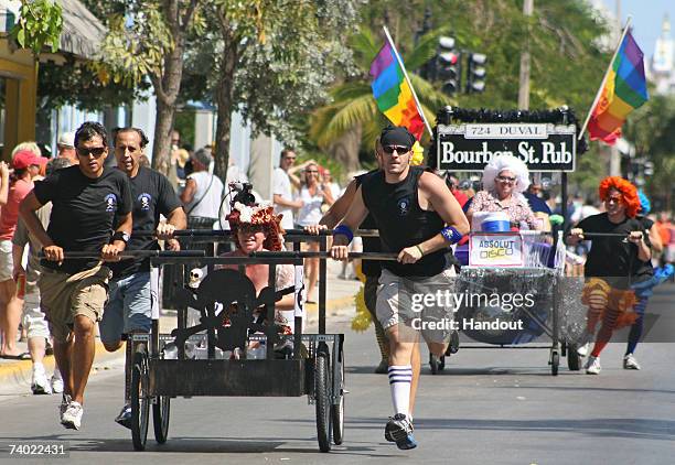 In this photo provided by the Florida Keys News Bureau, participants in the Conch Republic Red Ribbon Bed Race push their entries down Duval Street...