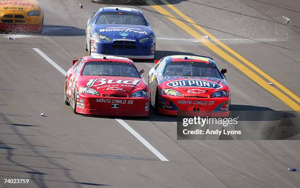 Dale Earnhardt Jr., driver of the Budweiser Chevrolet, waves to Jeff Gordon, driver of the DuPont Chevrolet, as fans throw beer cans on to the track,...