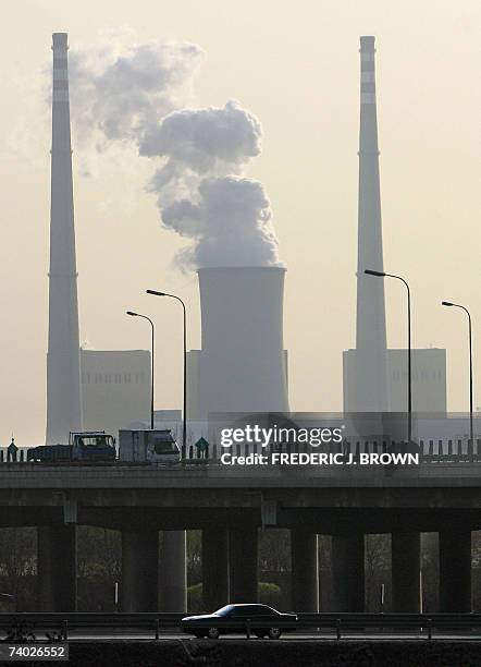 This picture taken 30 November, 2006 shows vehicles on a Beijing highway passing towering smokestack chimneys and cooling towers on the outskirts of...