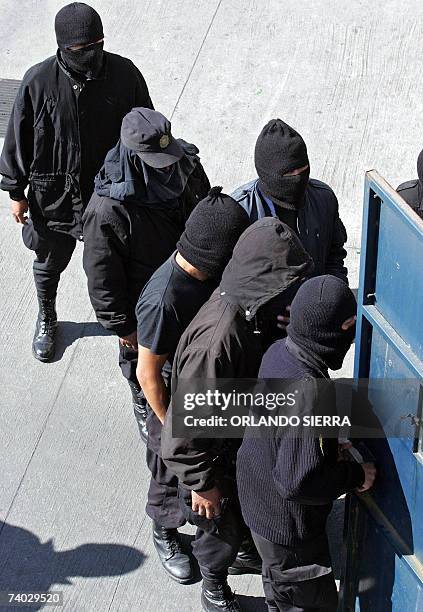 Integrantes del Nucleo de Accion Rapida de la Policia Nacional Civil , que permanecen con sus rostros cubiertos, permanecen en la entrada de la sede...