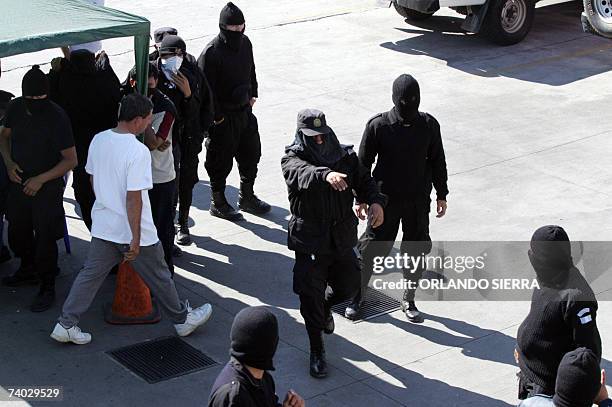 Integrantes del Nucleo de Accion Rapida de la Policia Nacional Civil , que permanecen con sus rostros cubiertos, se organizan cuando se amotinan en...