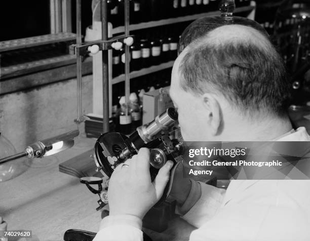 Scientist using a microscope at the Pioneer Health Centre in Queens Road, Peckham, circa 1935. The centre was opened by George Scott Williamson and...