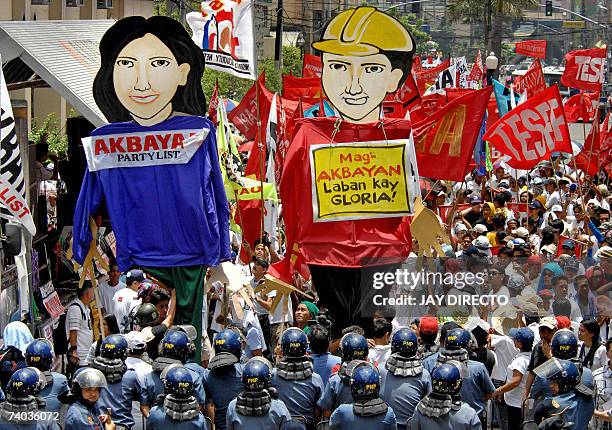 Leftist activists, carrying effigies reading "Workers united to topple President Gloria Arroyo" are blocked by anti-riot policemen as they attempt to...