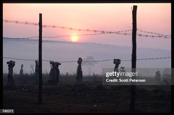 Tutsis carry supplies June 24, 1994 at the Nyarushishi Tutsi refugee camp on the Zaire border in Gisenyi, Rwanda. The camp is run by Hutu prefect...