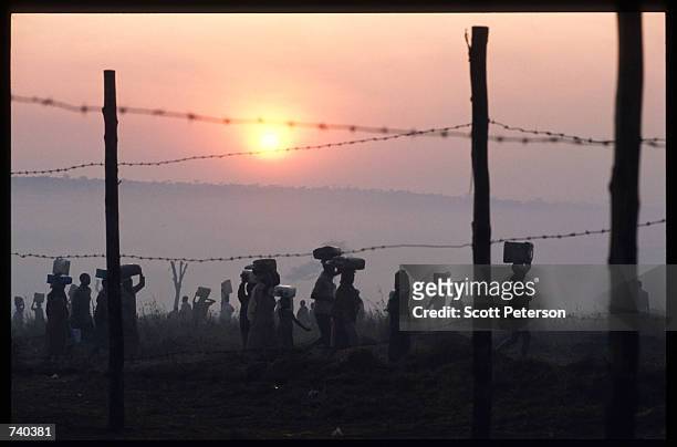 Tutsis carry supplies June 24, 1994 at the Nyarushishi Tutsi refugee camp on the Zaire border in Gisenyi, Rwanda. The camp is run by Hutu prefect...