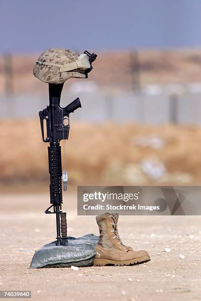 boots, rifle, dog tags, and helmet stand in solitude to honor fallen soldiers during a service held at al asad air base, iraq february 18, 2006. - boots rifle helmet stockfoto's en -beelden