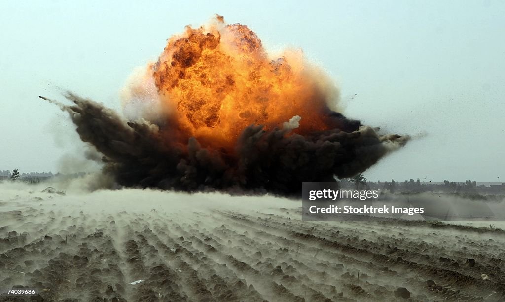 An explosion erupts from the detonation of a weapons cache.