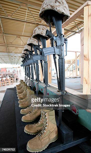 seven sets of dog tags, boots, rifles mounted into the ground with fixed bayonets, and helmets were used to represent six marines and one sailor at a memorial service april 18, 2006, at camp al asad, iraq. - boots rifle helmet stockfoto's en -beelden