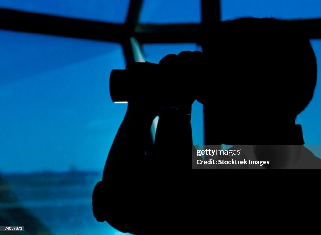 A Navy air traffic controller maintains an alert watch with binoculars in the control tower at Naval Air Station (NAS) Millington, Tennessee.