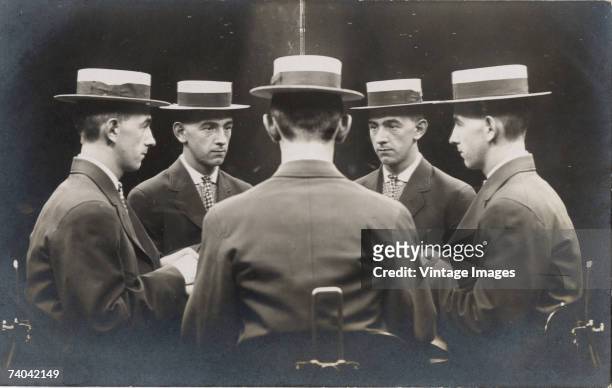 Mulitple exposure portrait shows a man in a straw boater from five different angles as he appears to sit at a table with himself, early 1900s.