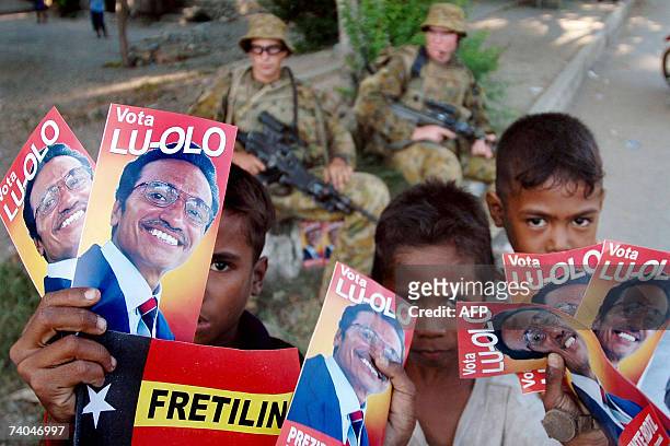 East Timorese children show photos of the presidential candidate of the Fretilin party as Australian soldiers take a rest in Dili, 02 May 2007. The...