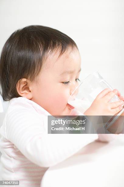 baby girl (15-18 months) drinking milk from glass - one baby girl only fotografías e imágenes de stock