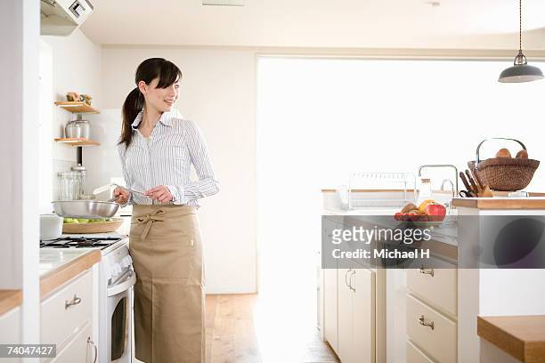 woman preparing food in kitchen - kitchen apron stock pictures, royalty-free photos & images