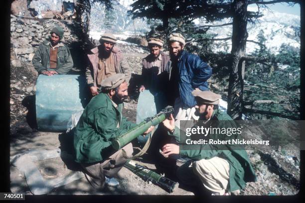 Guerrilla soldiers pose with weapons and military debris at a remote base in the Safed Koh mountains February 10, 1988 in Afghanistan. A...