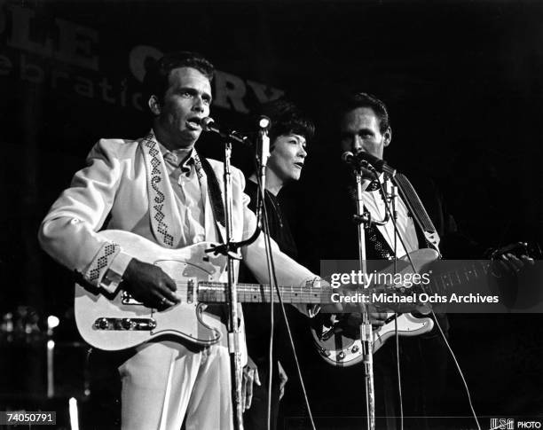 Country musician Merle Haggard performs on stage with singer Bonnie Owens and the bass player from his band "Merle Haggard & the Strangers" during...