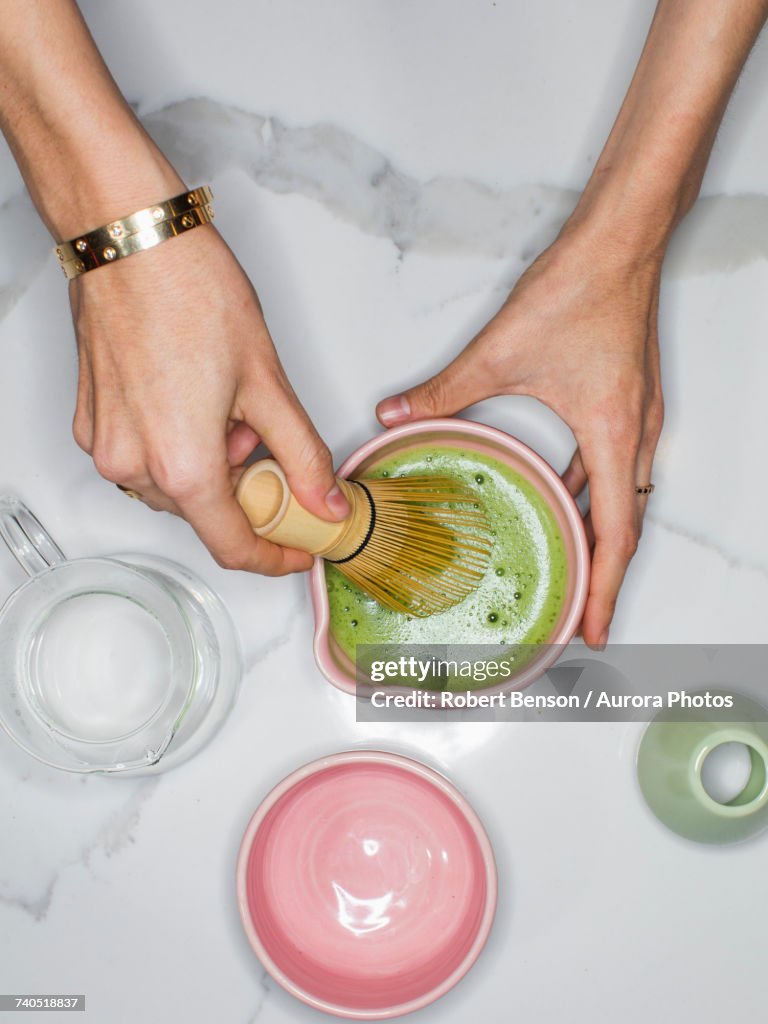 Person using whisk to prepare green tea matcha