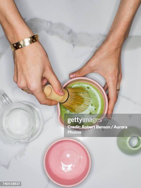 person using whisk to prepare green tea matcha - matcha stockfoto's en -beelden
