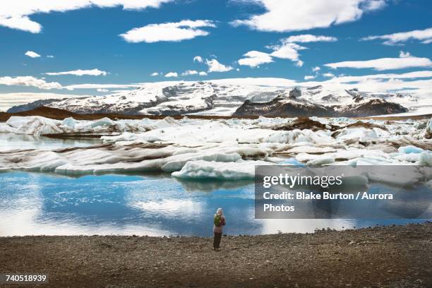 woman standing on shore and watching floating iceberg - jokulsarlon lagoon stock pictures, royalty-free photos & images
