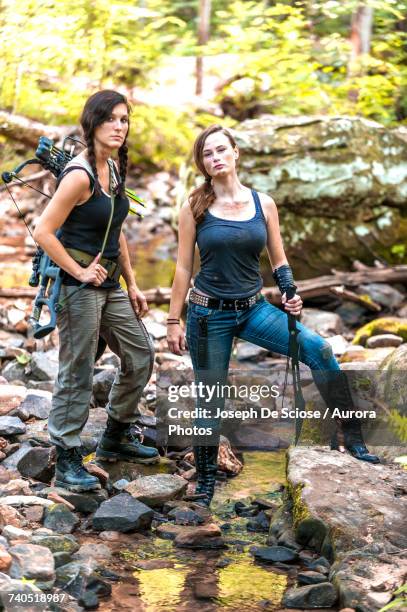 two young women carrying hunting gear in forest - crossbow stock pictures, royalty-free photos & images