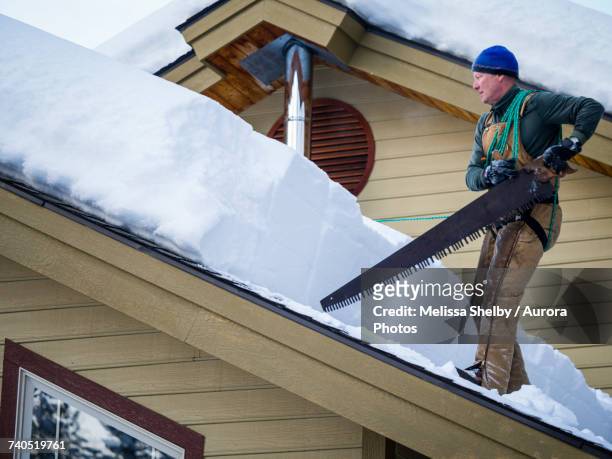 man clearing snow off of roof, mccall, idaho, usa - gezahnt stock-fotos und bilder