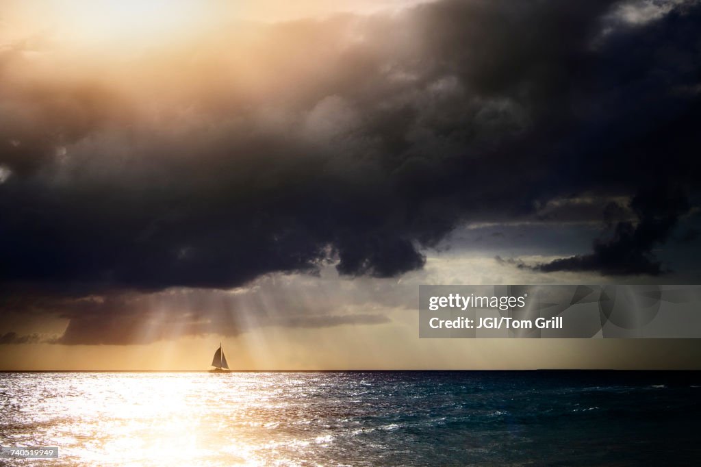 Sunbeams through storm clouds over sailboat