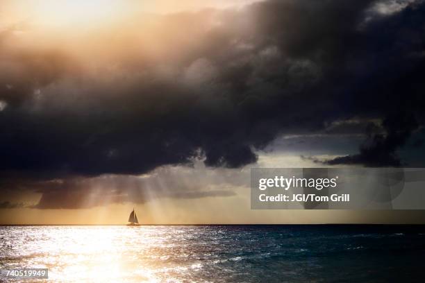 sunbeams through storm clouds over sailboat - sailboat storm stock pictures, royalty-free photos & images