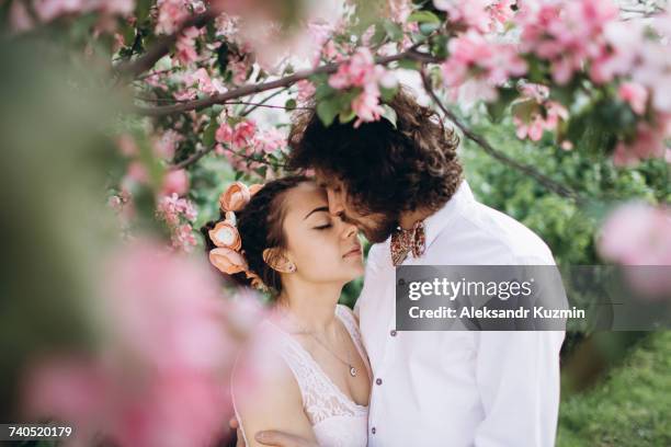 middle eastern couple kissing under flowering tree - arabic wedding stock pictures, royalty-free photos & images