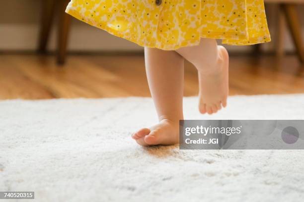 barefoot caucasian baby girl walking on rug - baby dancing stock-fotos und bilder